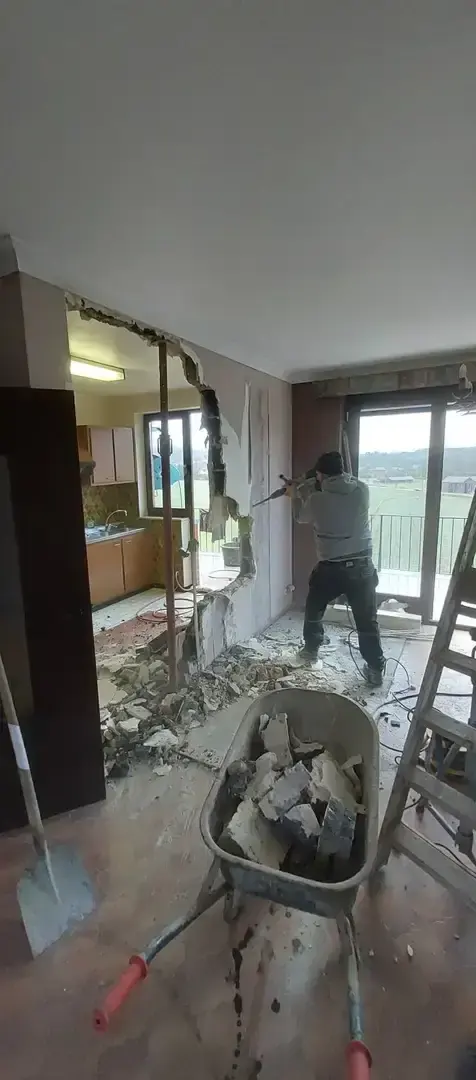 Démolition d'un mur intérieur avec brouette de gravats