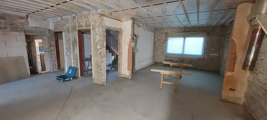 Grande pièce avec chape coulée et murs en pierre apparents