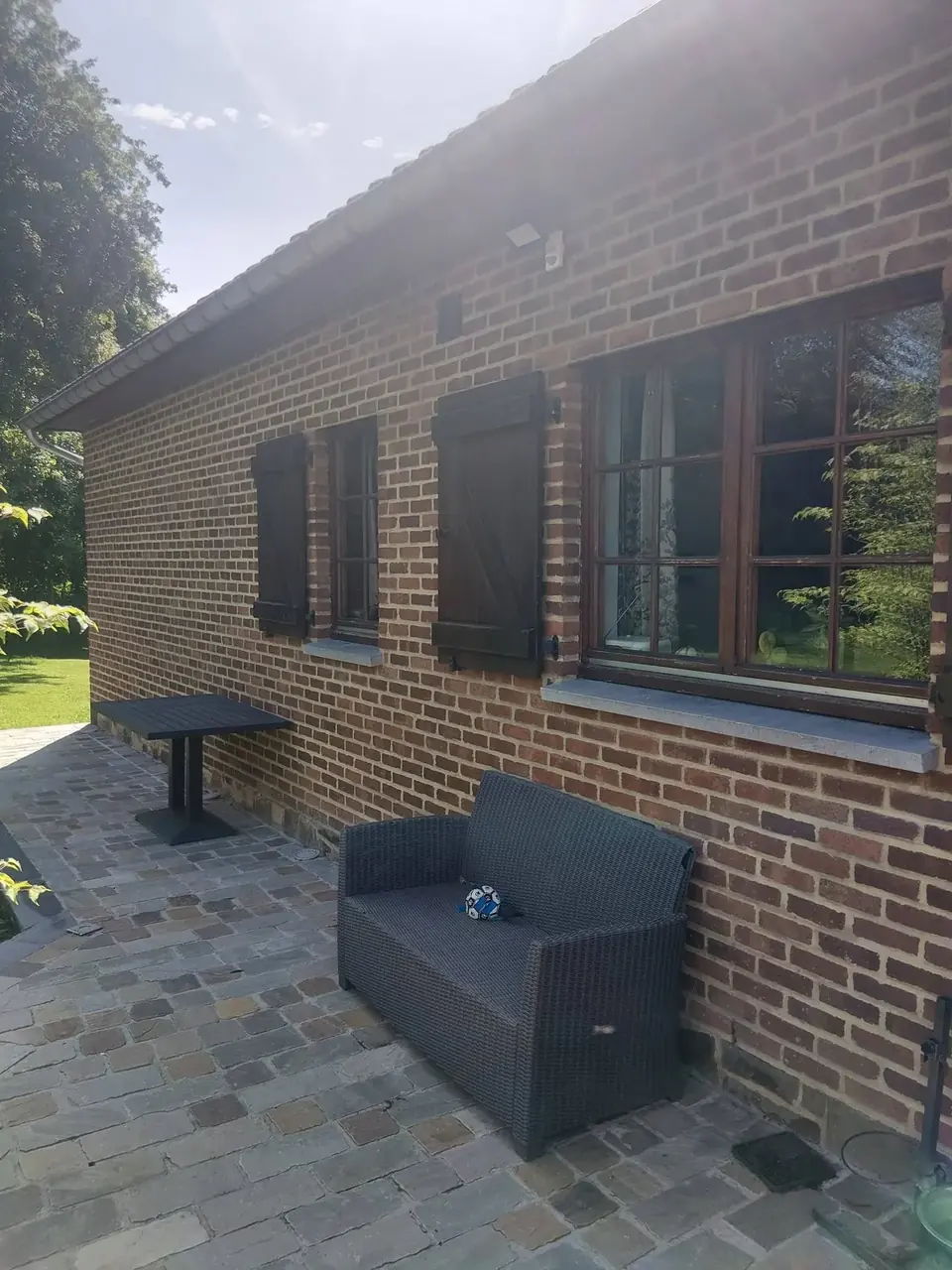 Fenêtre et volets sur façade en briques avec fauteuil de jardin