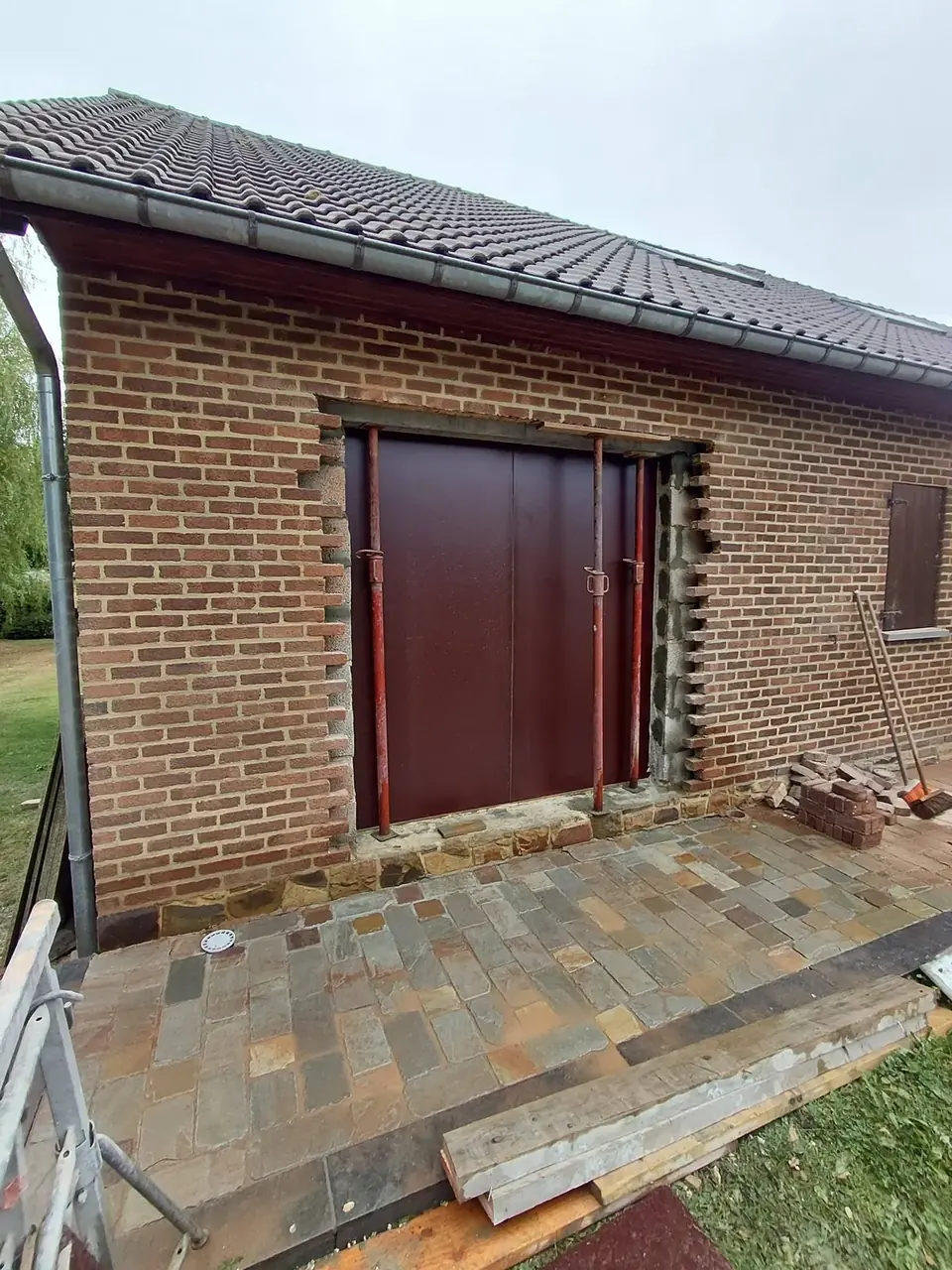 Grande porte rouge de chantier dans un mur en briques