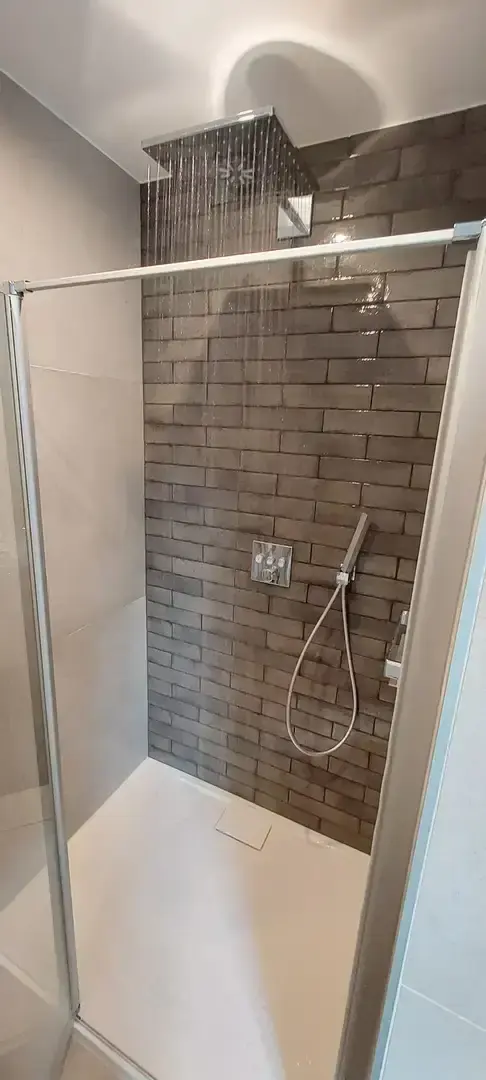 Douche carrelée avec pomme de pluie et paroi vitrée
