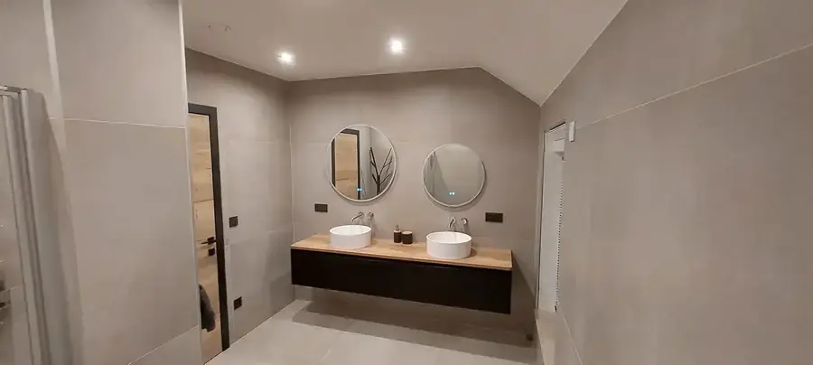 Salle de bain avec double vasque, miroirs ronds et carrelage gris
