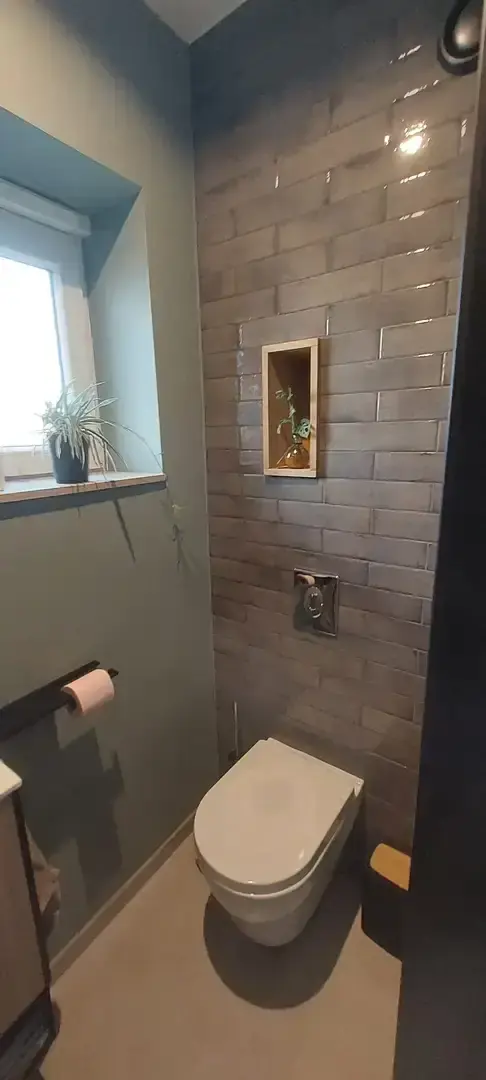 WC suspendu avec carrelage brillant et niche