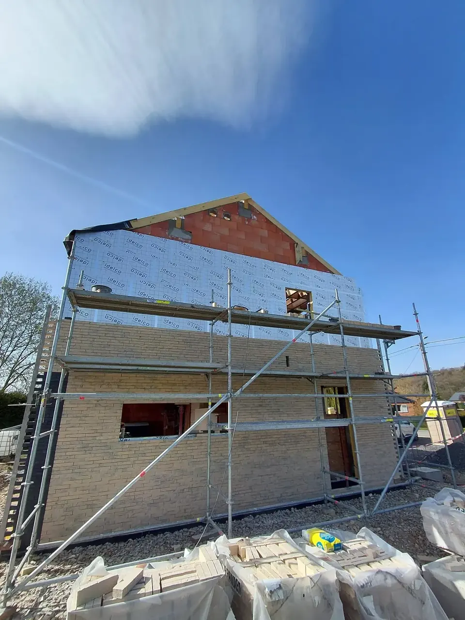 Maison en briques beige avec échafaudage et isolant en toiture