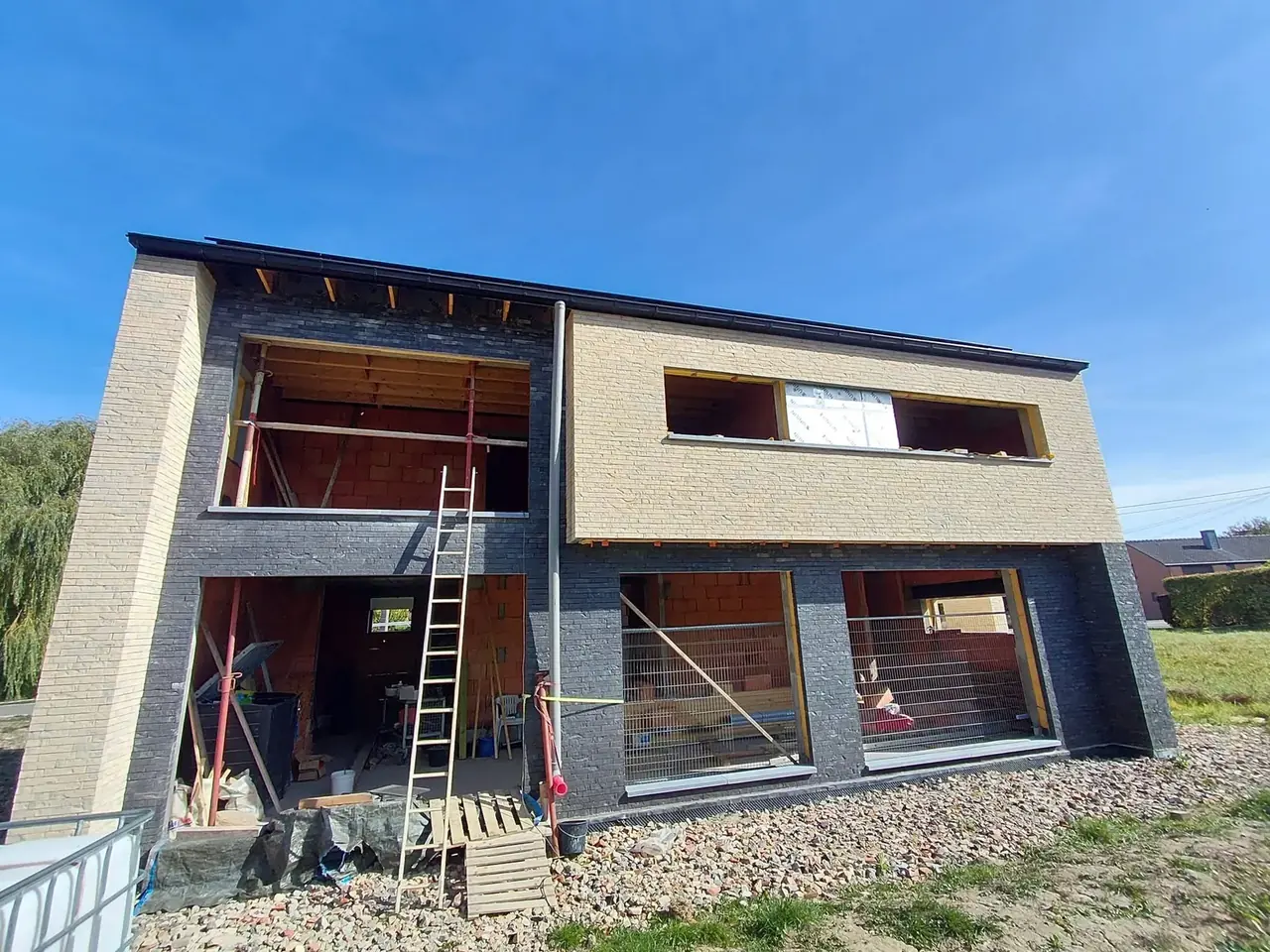 Façade en briques beige et briques noires avec grandes ouvertures