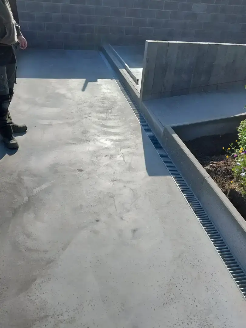 Nouvelle terrasse de béton avec caniveau et mur de soutènement