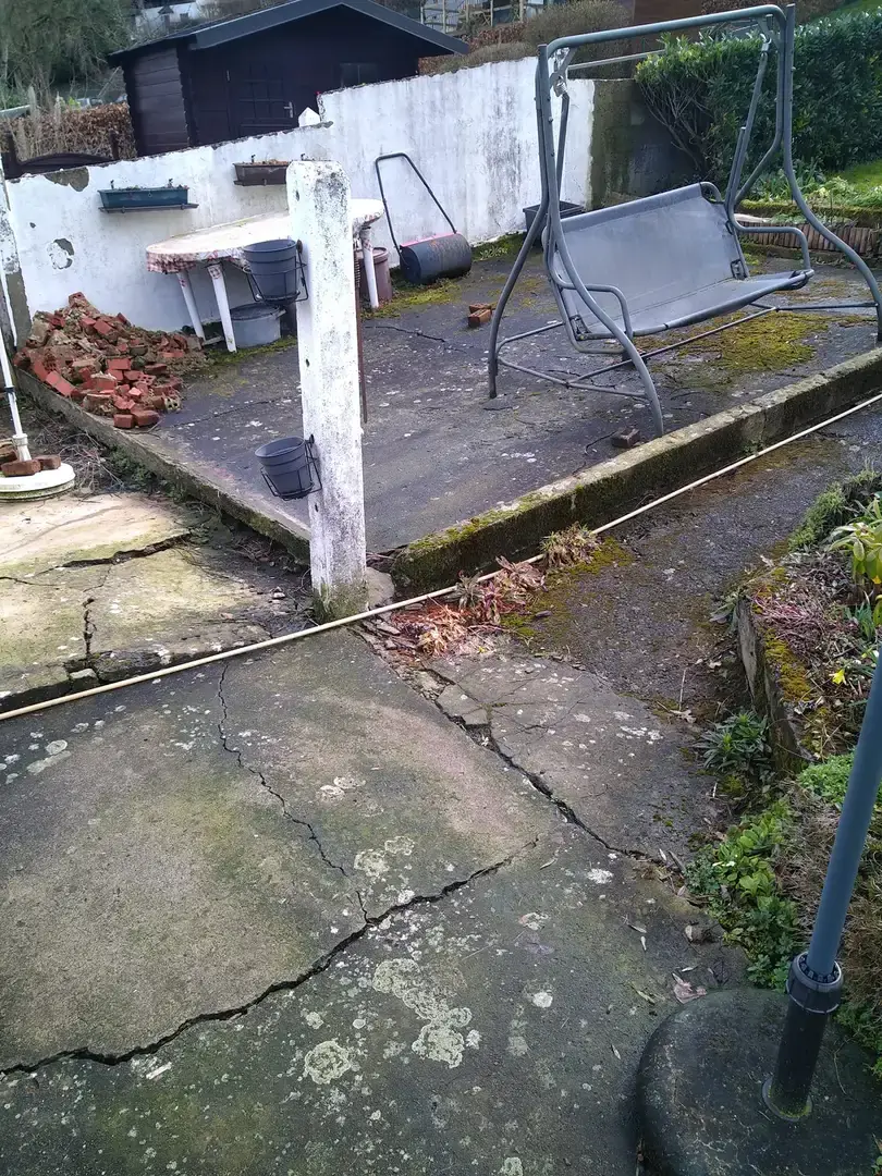 Ancienne terrasse fissurée avec mobilier de jardin avant les travaux