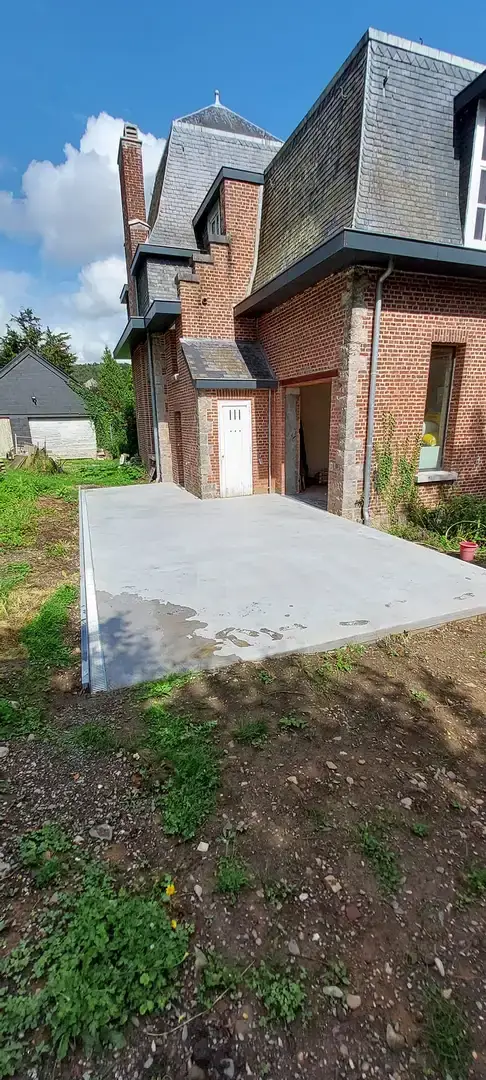 Terrasse en béton devant une maison en briques