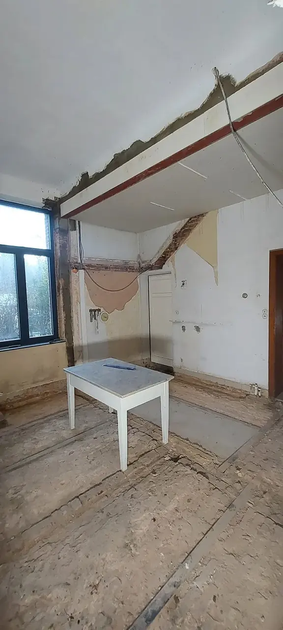 Pièce en démolition avec table blanche et fenêtre