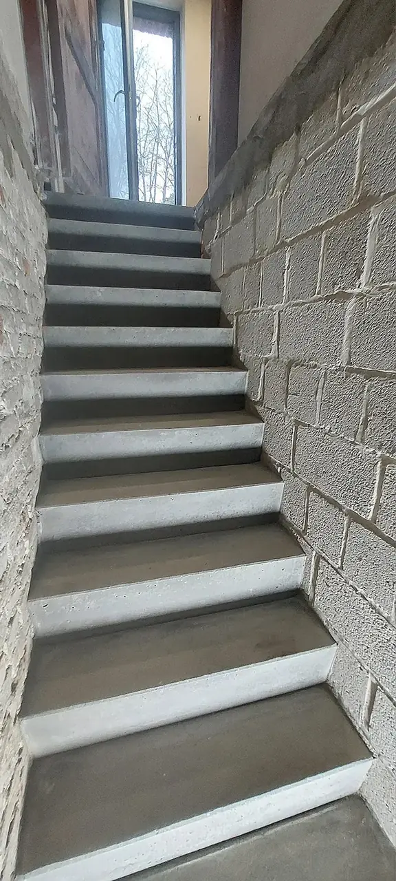 Escalier en béton avec mur en blocs et fenêtre en haut