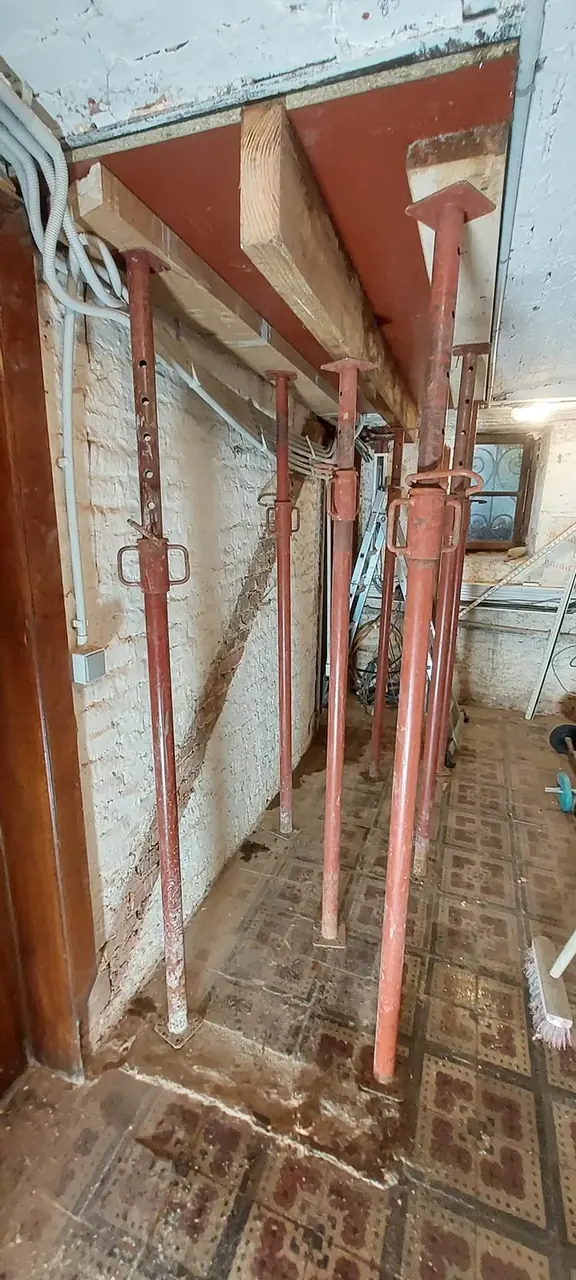 Étais métalliques rouges dans un couloir carrelé ancien