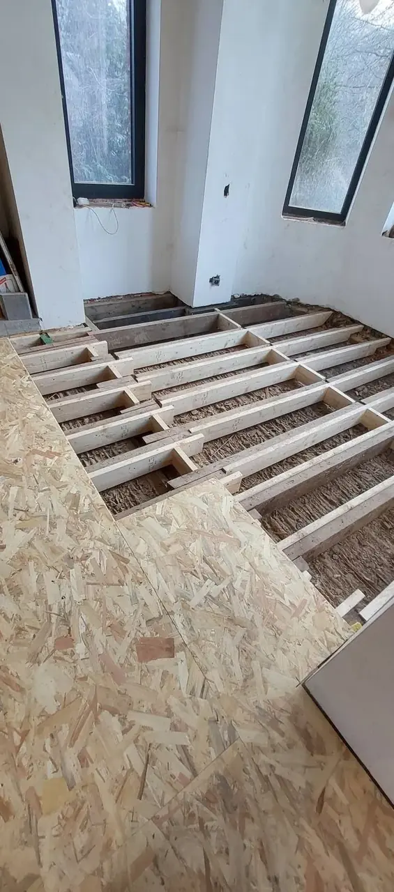 Plancher en cours de pose dans une pièce avec grandes fenêtres