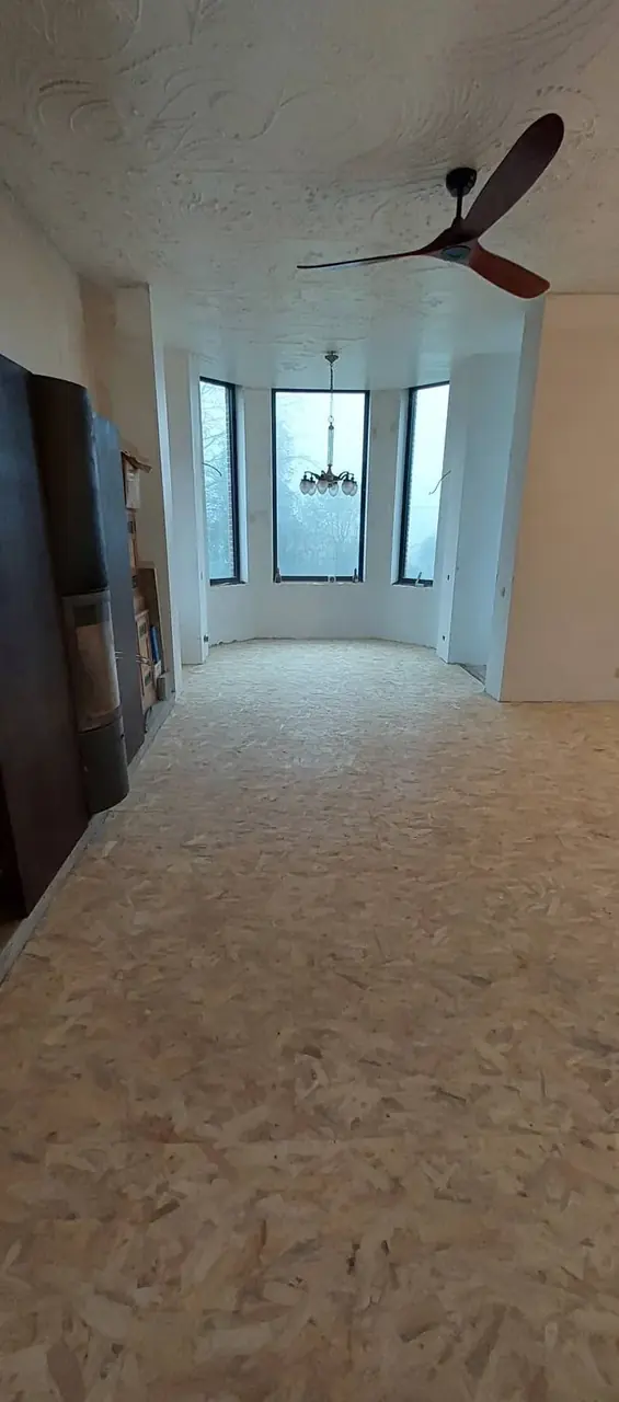 Pièce avec plancher en panneaux OSB, grandes fenêtres et ventilateur de plafond