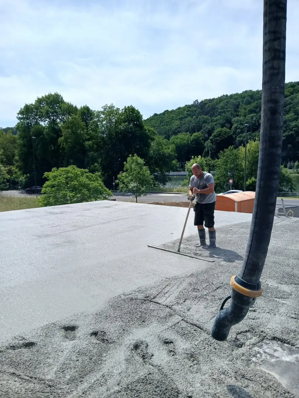 Béton lissé à la règle sous la pompe, ouvrier au loin