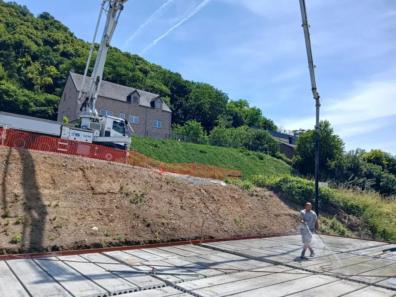 Coulage de la dalle avec grue et pompe, maison voisine à l'arrière