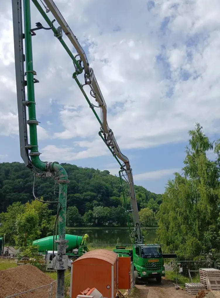 Pompe à béton verte et camion devant la vallée