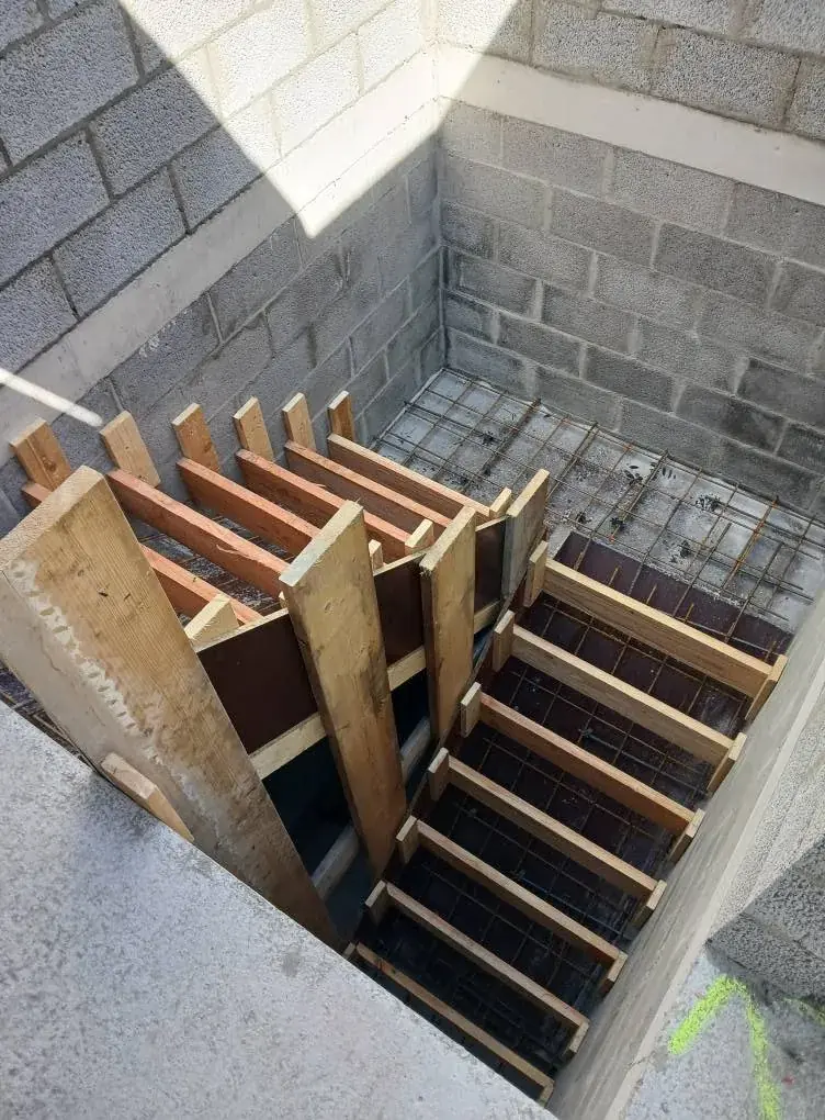 Coffrage en bois d'un escalier en béton dans une cage en blocs