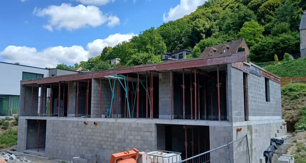 Façade en blocs avec étais et poutres, colline à l'arrière