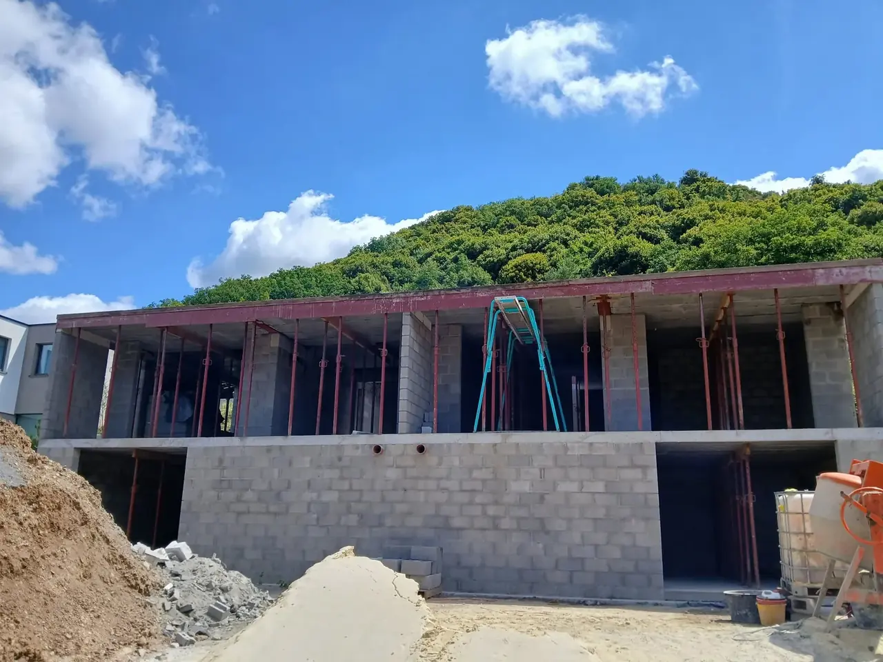 Façade en blocs avec ouvertures et étais sous ciel bleu
