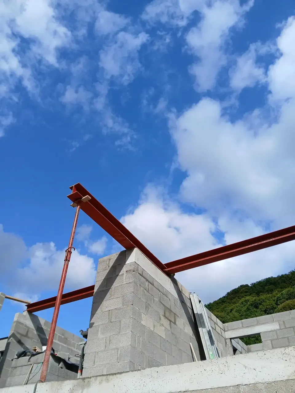 Mur de pignon en blocs avec poutre métallique rouge et ciel bleu