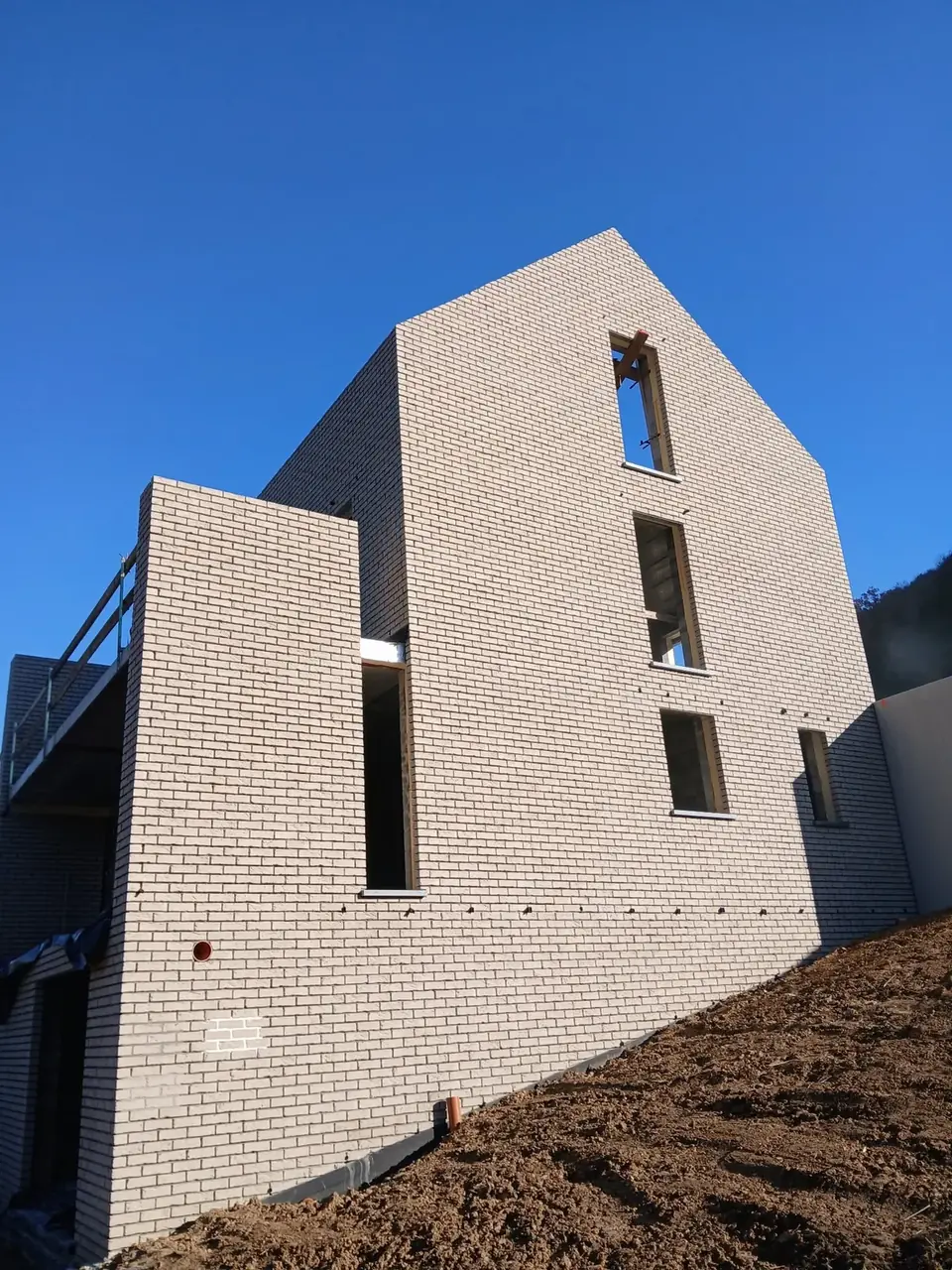 Pignon de brique beige avec fenêtres hautes sous un ciel bleu