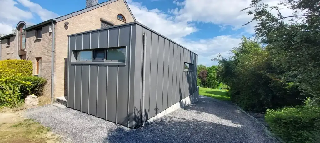 Annexe à bardage de zinc gris le long d'une allée de gravier