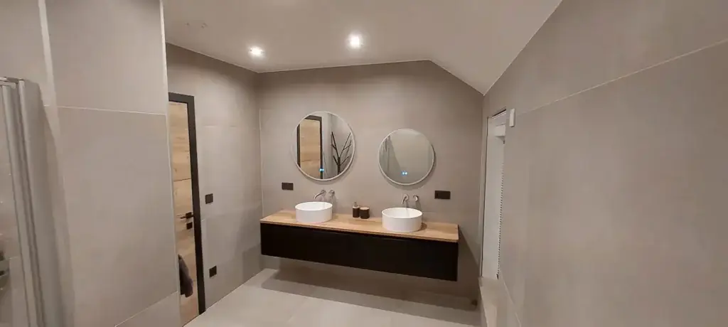Salle de bain terminée : double vasque sur meuble en bois et deux miroirs ronds