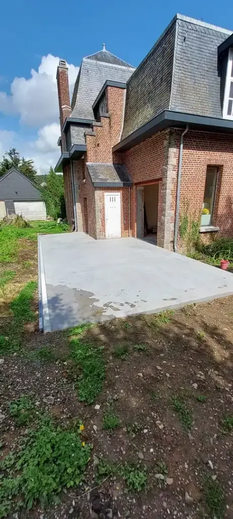 Terrasse en béton lissé le long d'une maison en briques rouges