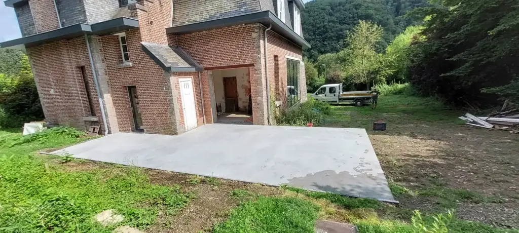 Terrasse en béton lissé devant une maison en briques rouges