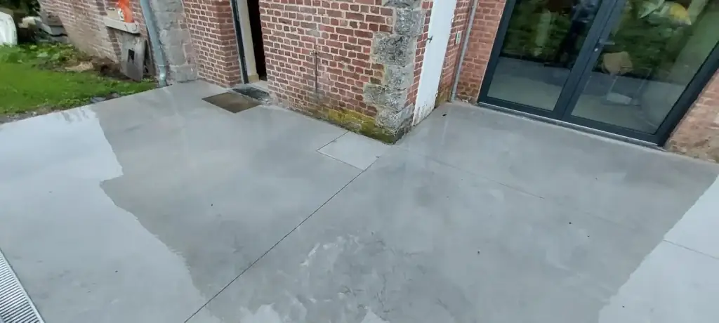 Terrasse en béton lissé devant de grandes baies vitrées