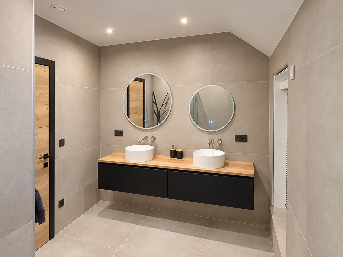 Salle de bain aménagée : double vasque sur meuble noir et bois, miroirs ronds