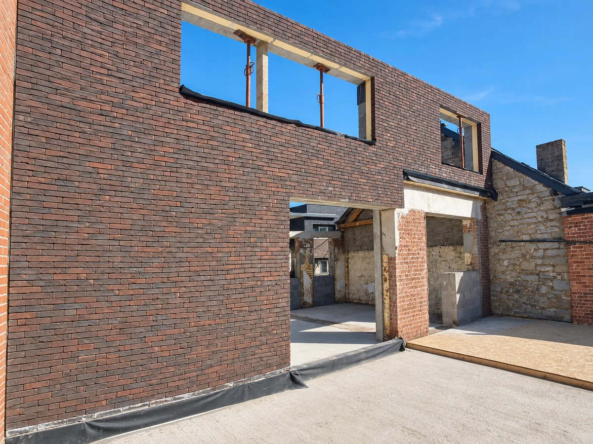 Transformation d'un bâtiment : grand mur en briques percé de nouvelles baies